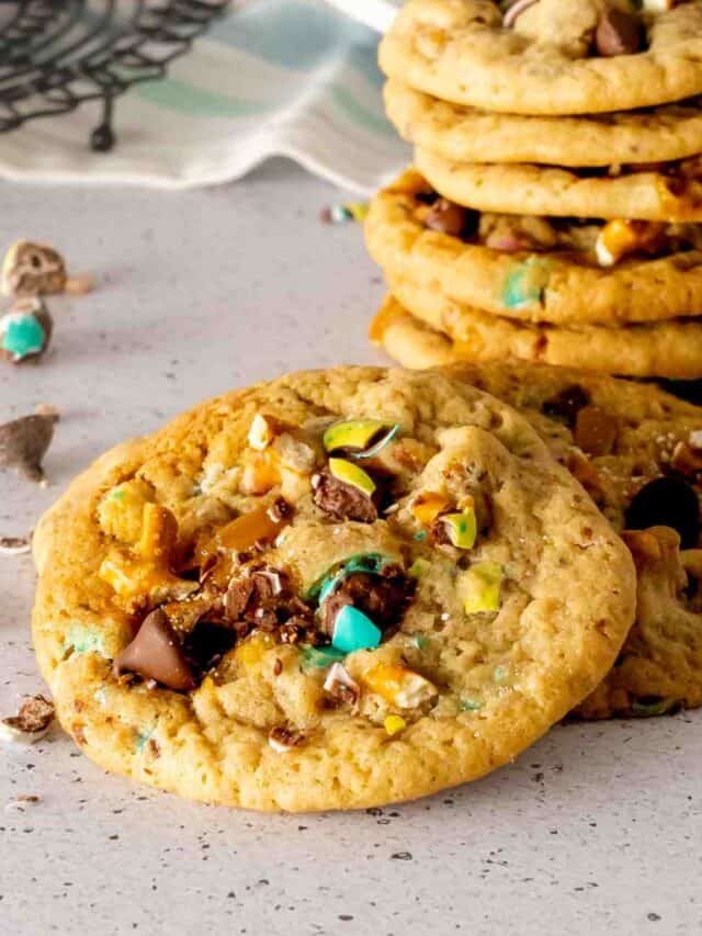 A stack of Easter trash cookies with M&M's, caramels, pretzels, and chocolate chips.