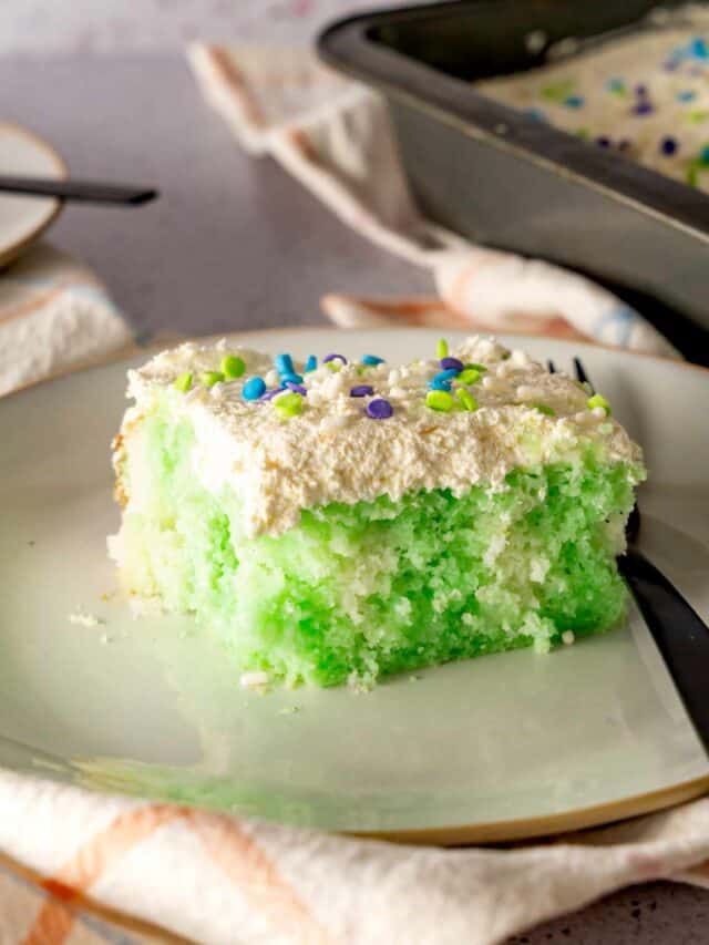 A slice Lime Poke Cake decorated with spring sprinkles.