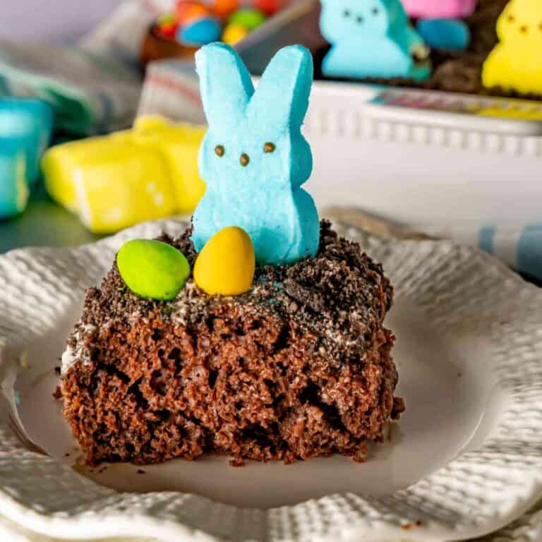 A slice of Easter Pudding Poke on a decorative plate with a blue bunny peep.