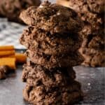 Mexican Chocolate Cookies stacked five high with cinnamon sticks in the background.