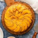Birdseye view of a whole bourbon peach upside down cake on a wooden server.