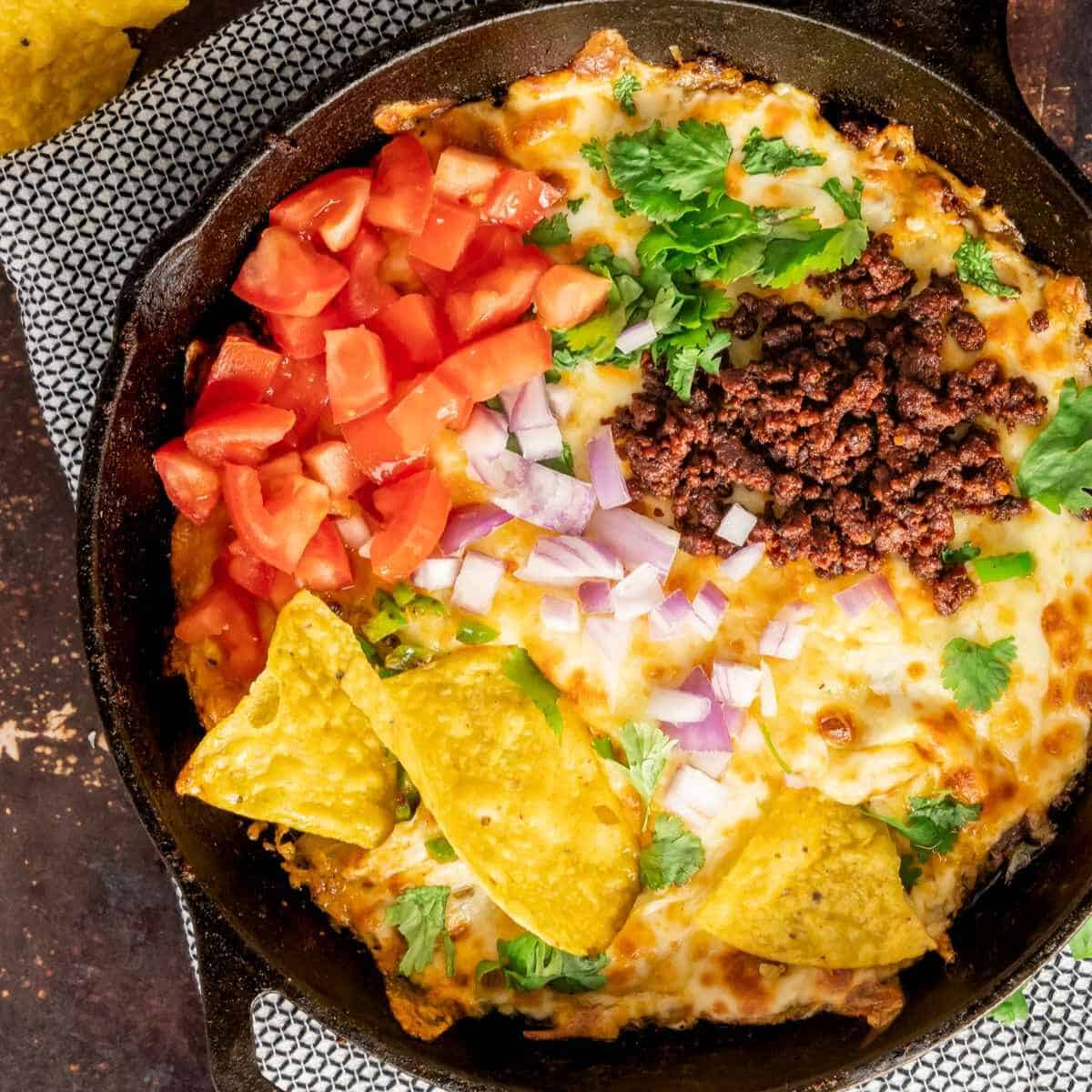 Birdseye view of queso fundido topped with diced tomatoes, jalapenos, chorizo, and red onions.