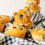 Freshly baked old fashioned blueberry muffins recipe in white muffin liners on a blue checkered napkin.