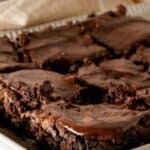 A tray of sliced chocolate zucchini bars topped with ganache frosting.