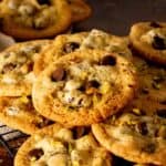 Pistachio chocolate chip cookies stacked on a square cooling rack.