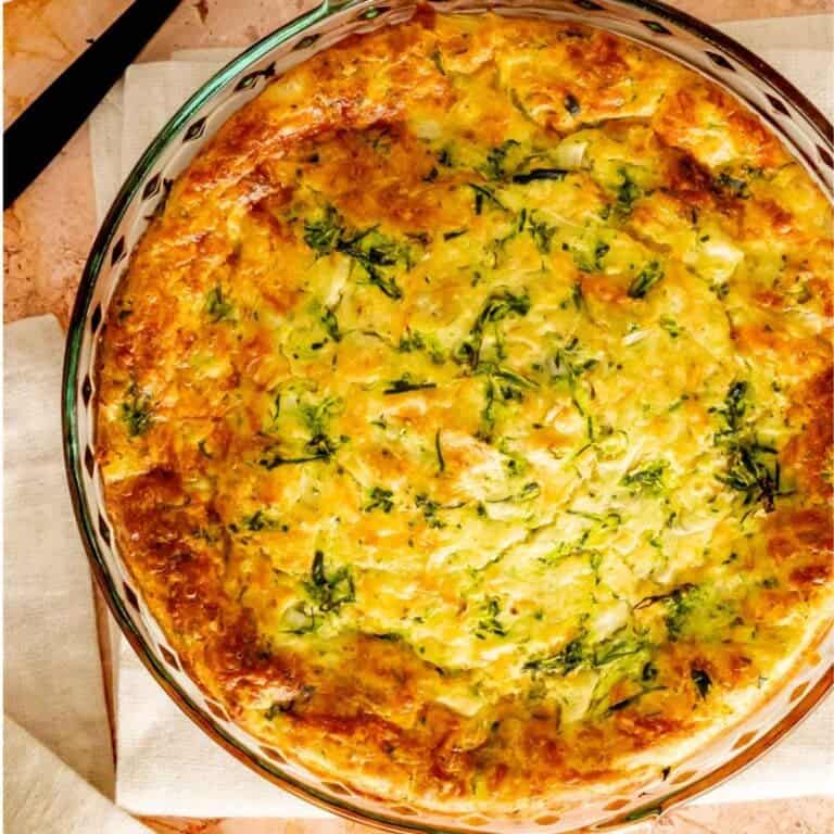 Bisquick Zucchini Quiche in a glass pie plate with a serving utensil.