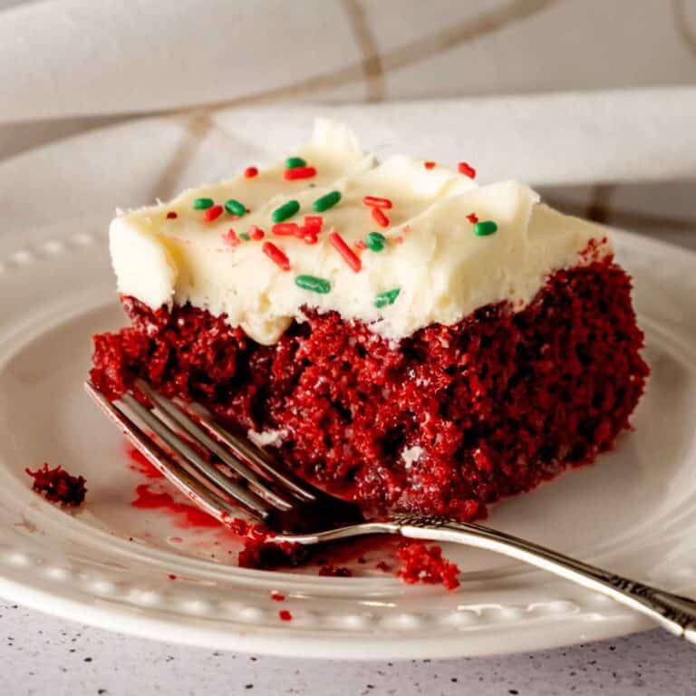 A slice of red velvet poke cake topped with cream cheese frosting.