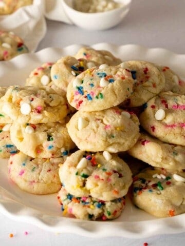 A white scalloped platter stacked with confetti cookies.