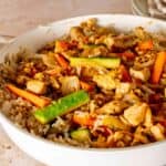 Bowl of hibachi chicken and rice with chopped vegetables.