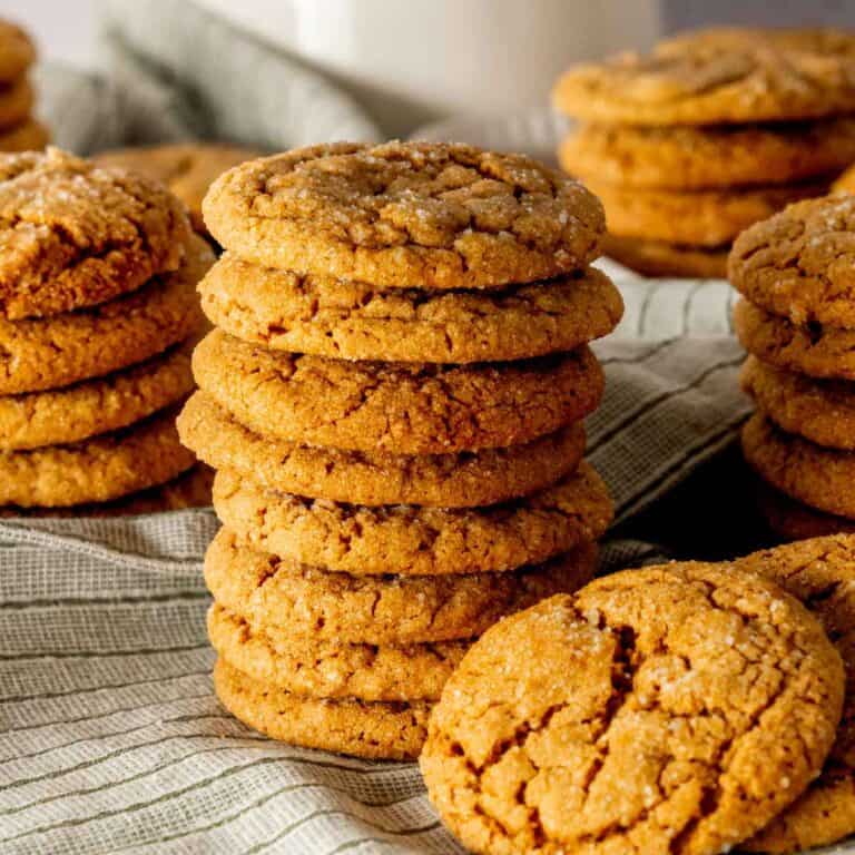 Molasses cookies in stacks with a white mug in the background.