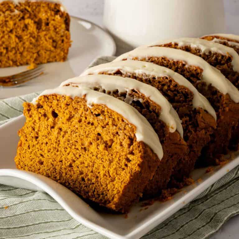 Sliced pumpkin bread with spice cake mix that is frosted with maple cream cheese frosting.