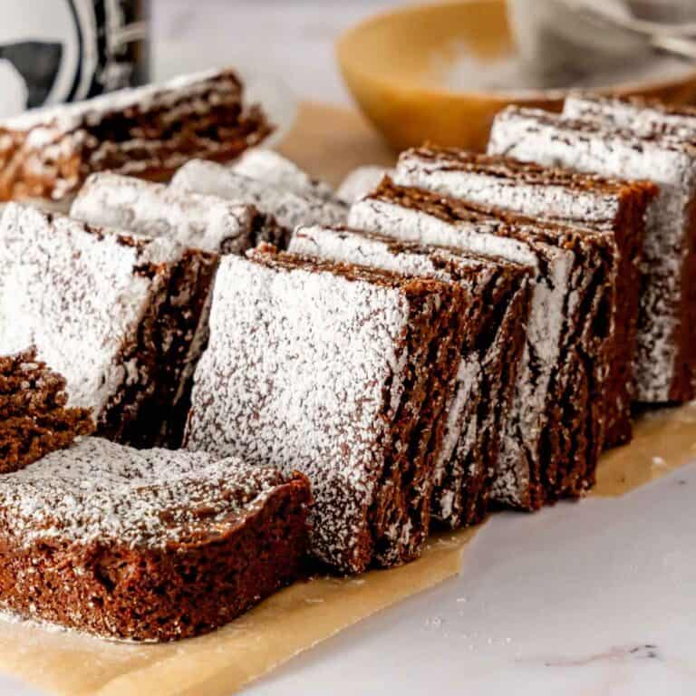 Gingerbread Brownies with powdered sugar sliced and resting on parchment paper.