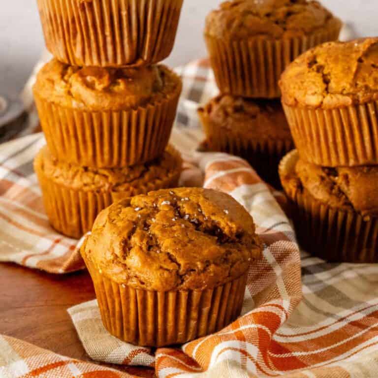 Stacked gluten free pumpkin muffins on autumn themed linen napkins.