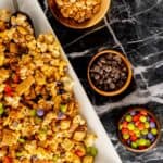 Halloween Monster Munch recipe on a large serving platter with bowls of candy and nuts.