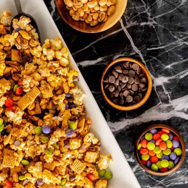 Halloween Monster Munch recipe on a large serving platter with bowls of candy and nuts.