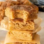 Three snickerdoodle blondies stacked with unbleached parchment paper between them.