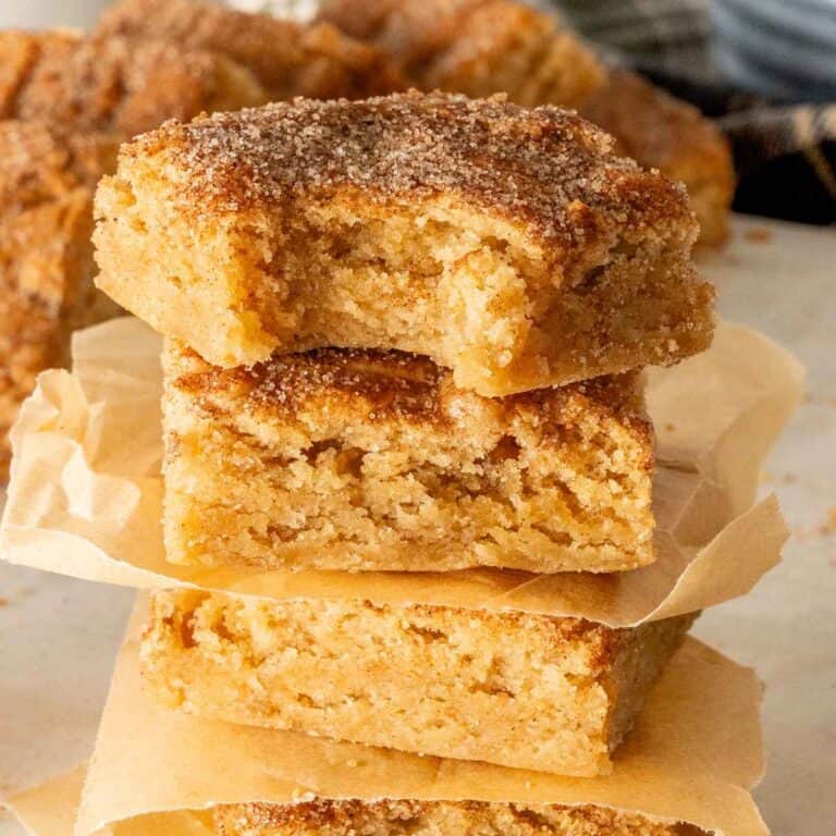 Three snickerdoodle blondies stacked with unbleached parchment paper between them.