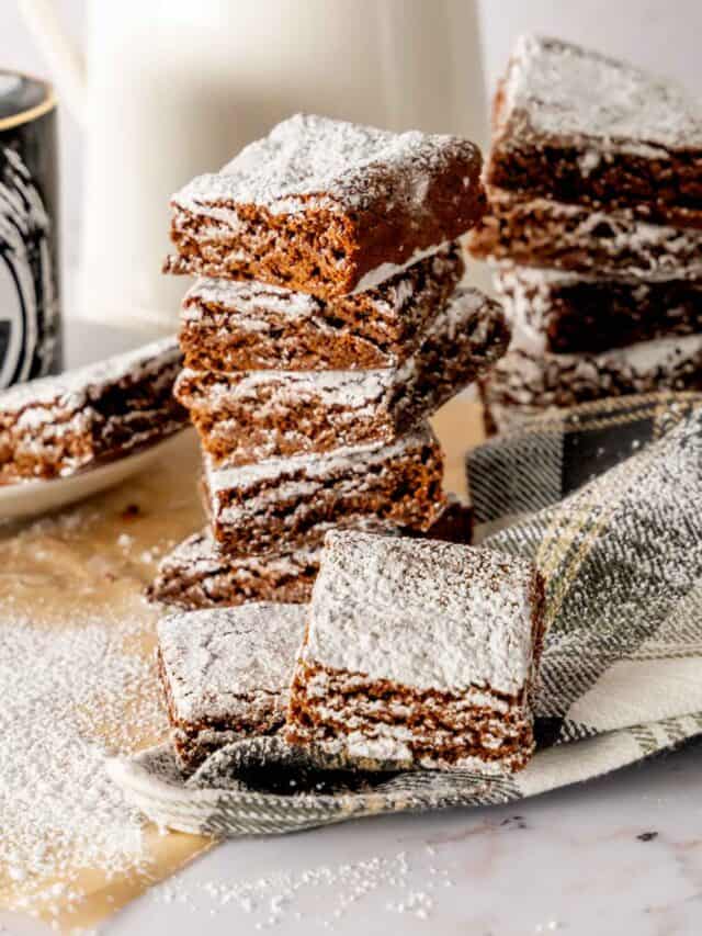 A stack of gingerbread brownies dusted with powdered sugar.