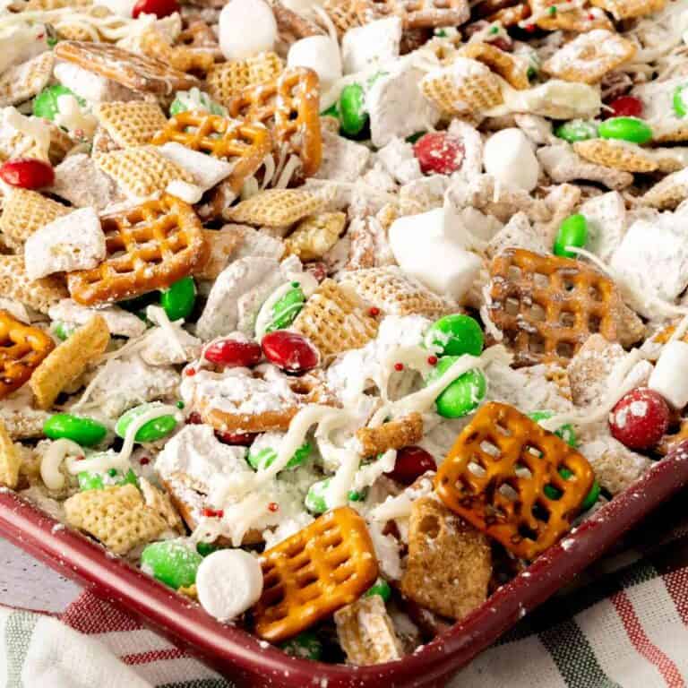 A red baking tray with Christmas White Trash with almond bark and red and green candies.