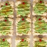 Twelve Christmas cookie bars decorated with green buttercream trees.