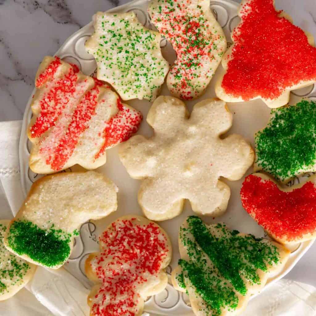 Birds eye view of cream cheese sugar cookies for Christmas on decorative plate.