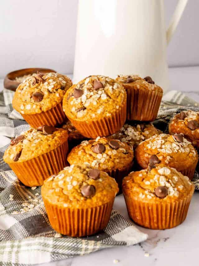 Stacked oatmeal chocolate chip muffins with a milk pitcher in the background.