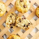 Chocolate Chip Banana Muffins scattered on a serving tray with one cut in half.