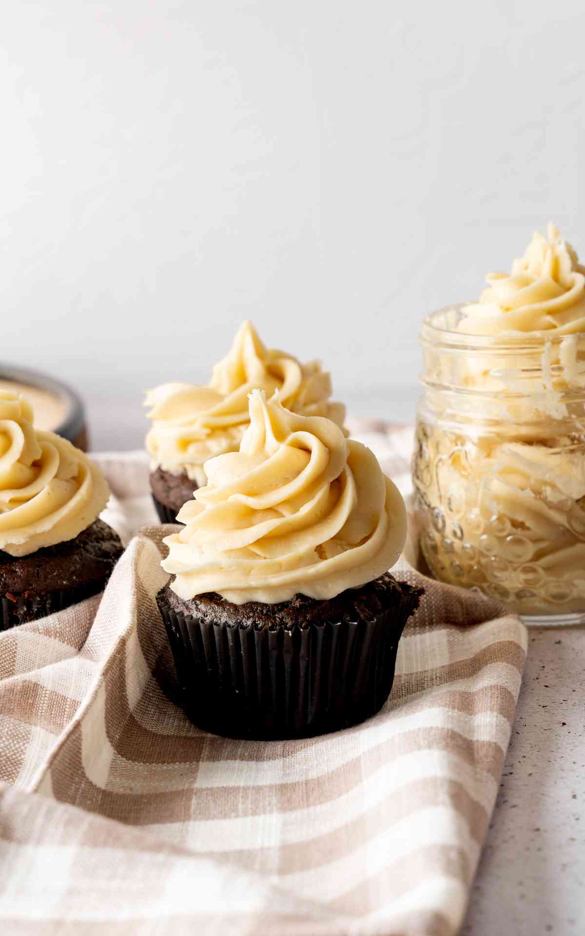 Cupcakes topped with salted caramel icing on a checkered napkin.
