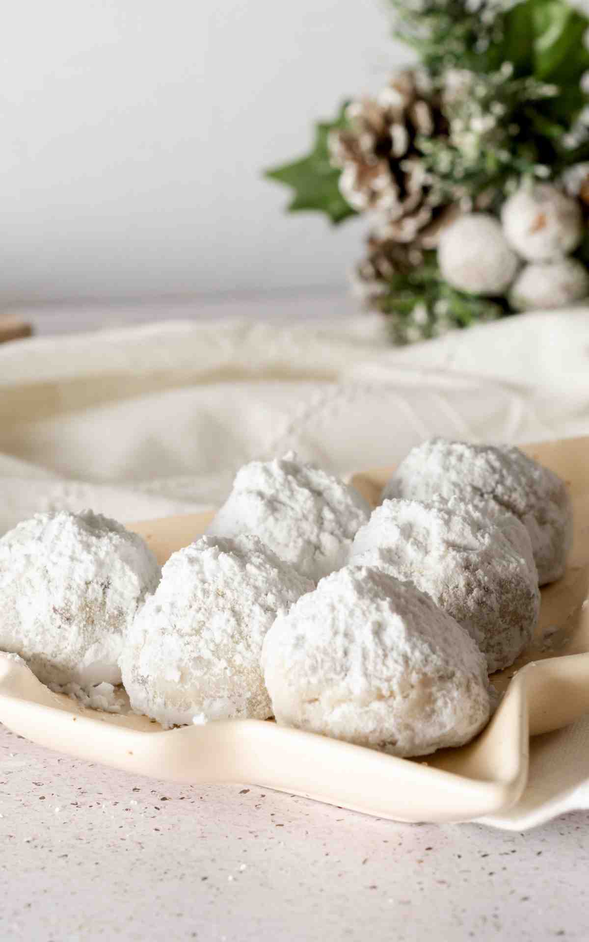 Chocolate chip snowball cookies on a Christmas tree shaped plate.