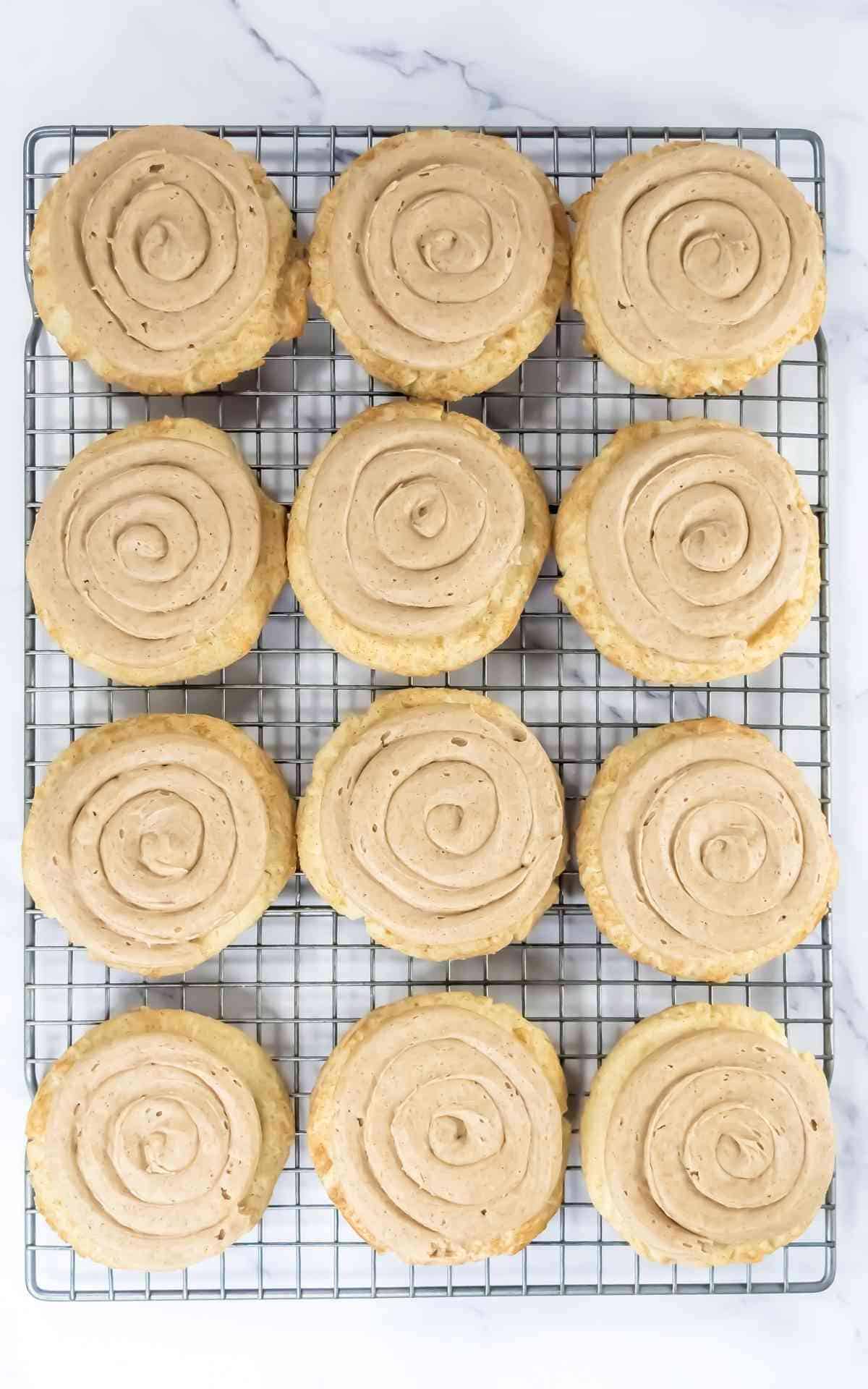 Frosted churro cookies on a wire rack with cinnamon buttercream.