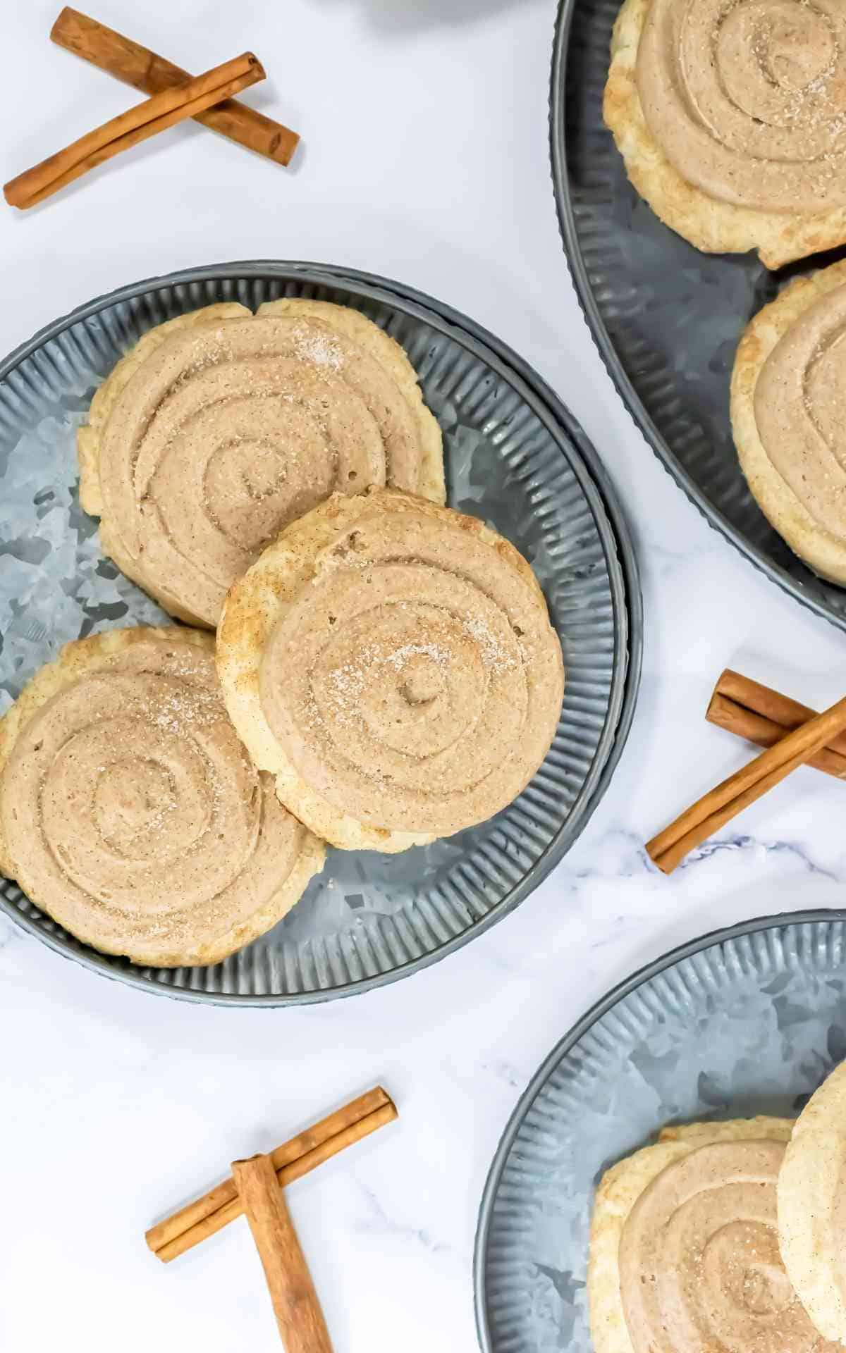 Overhead of churro cookies on a metal plate with cinnamon sticks.