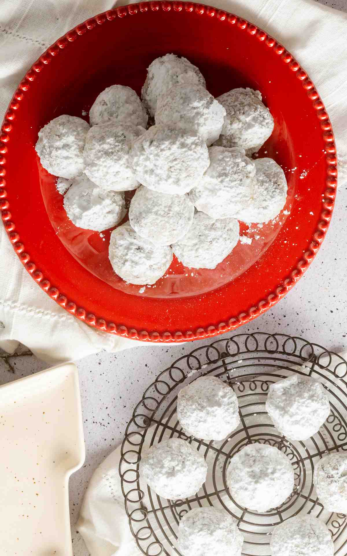 Overhead photo of snowball cookies on a plate and a wire rack.