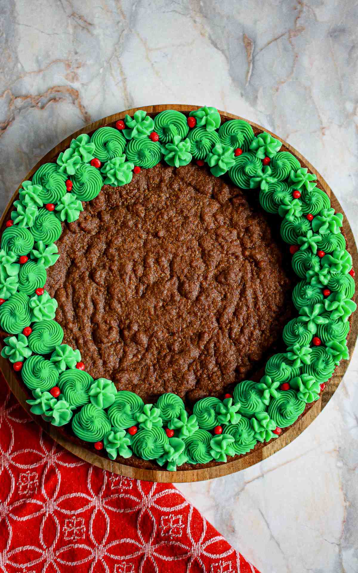 A green and red decorated cookie cake on a serving board.