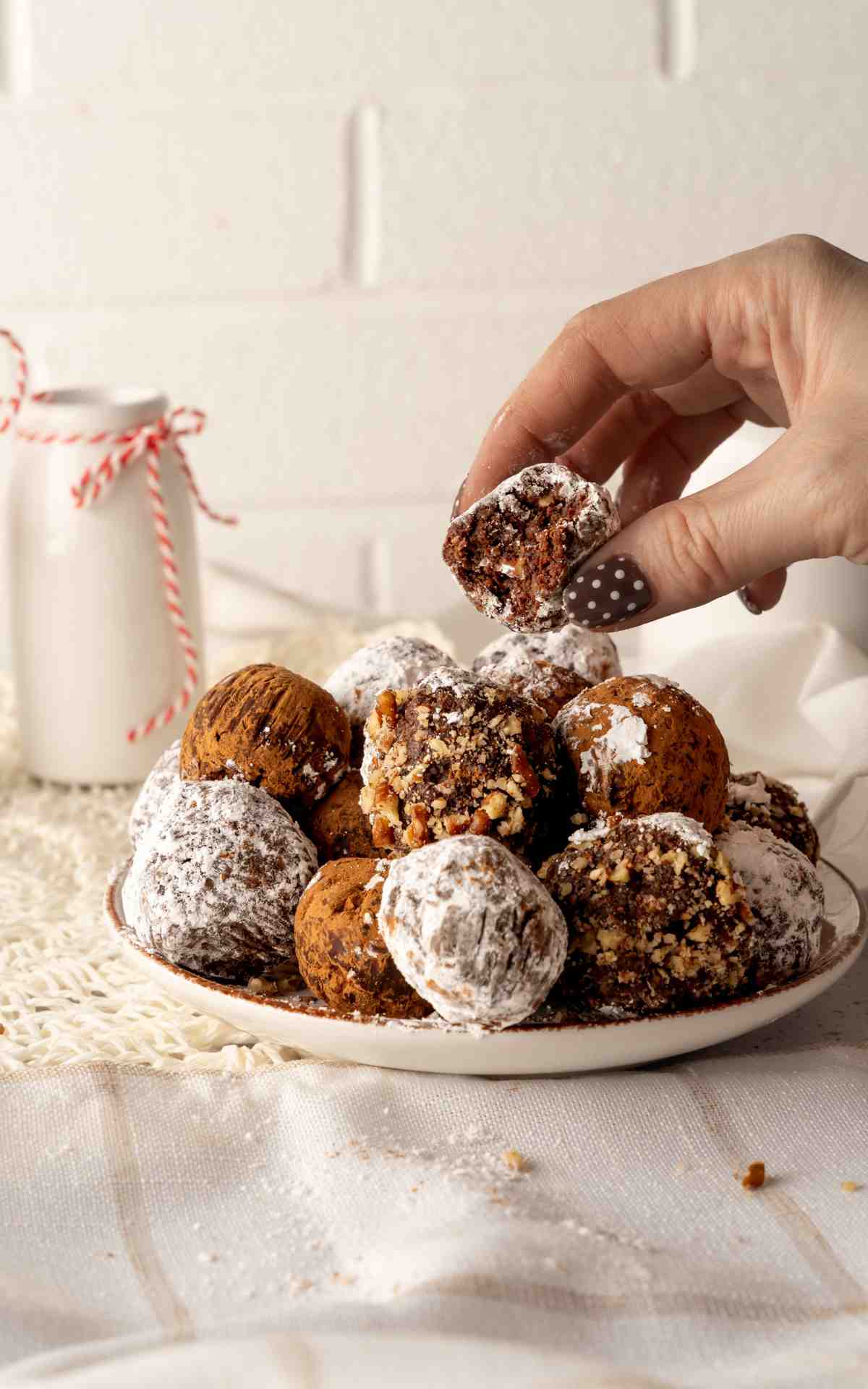 A manicured hand holding up a bitten into rum balls.