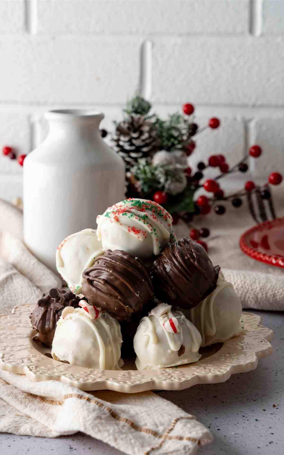 A stack of peppermint cookie dough balls and festive Christmas no bake balls.