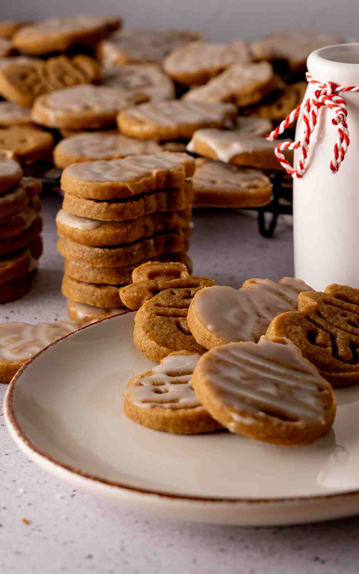 A plate of cutout cookies with vanilla glaze and a glass of milk.