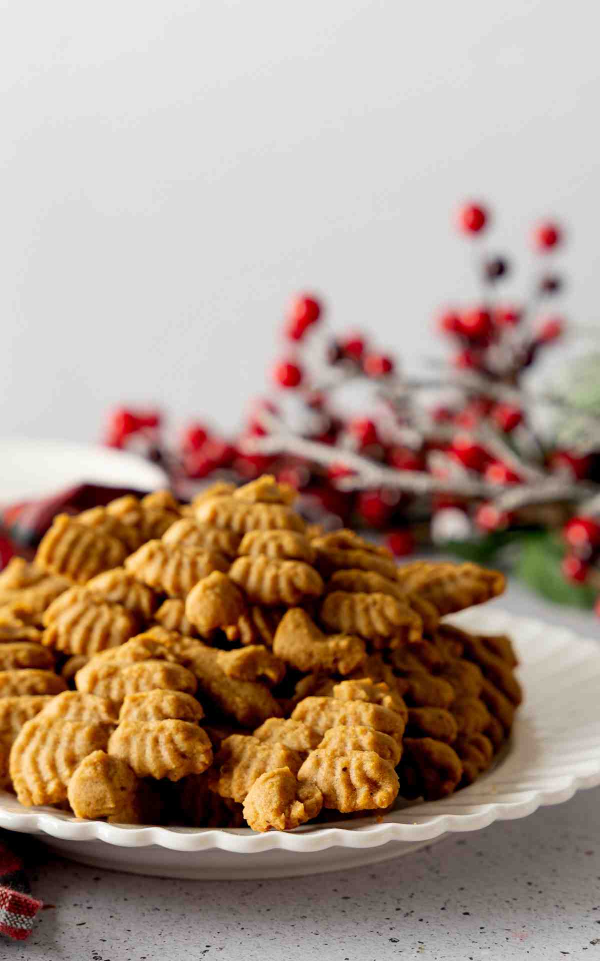 A white plate of stacked molasses cookies made with a cookie press.