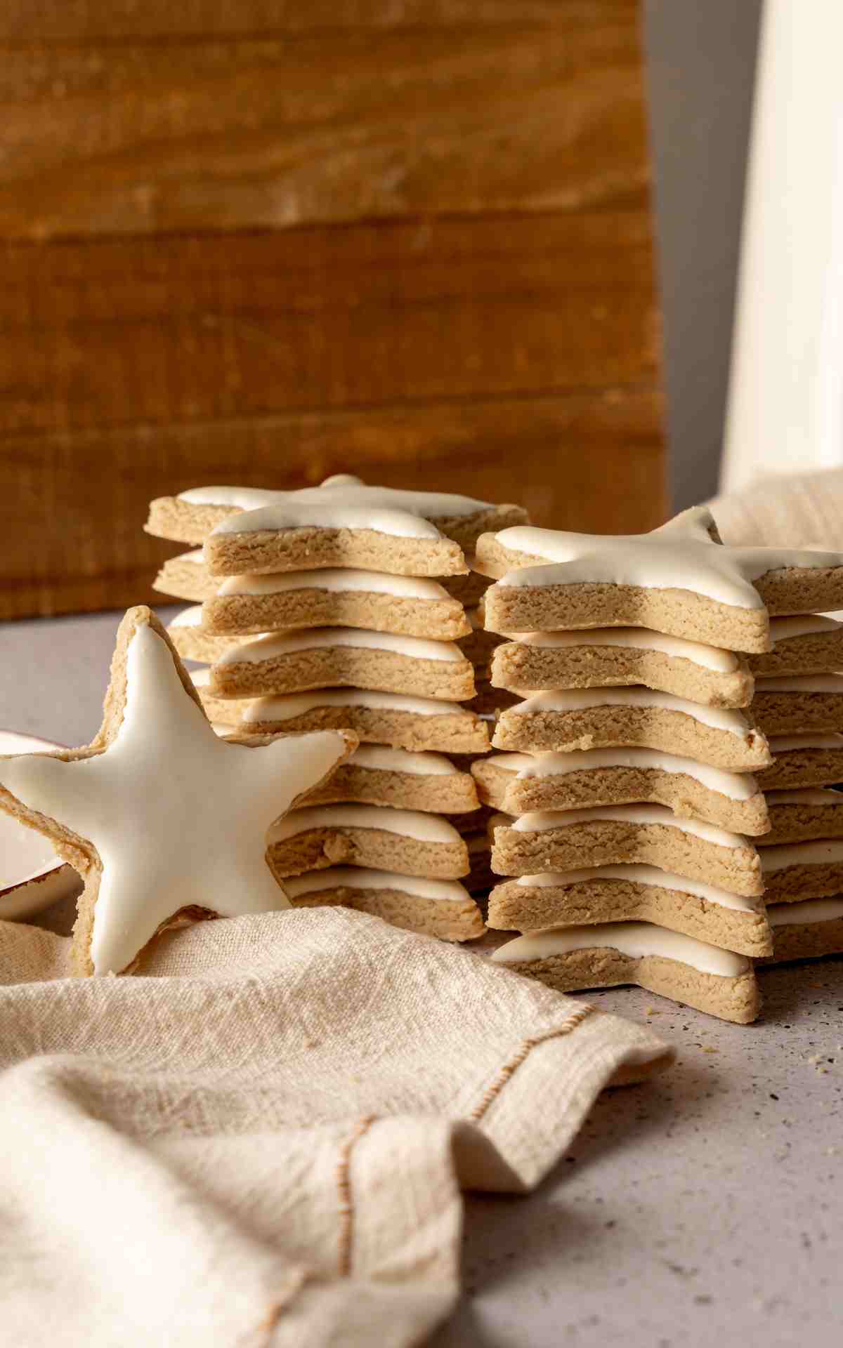 Two stacks of Zimtsterne star cookies with a cookie propped in front.
