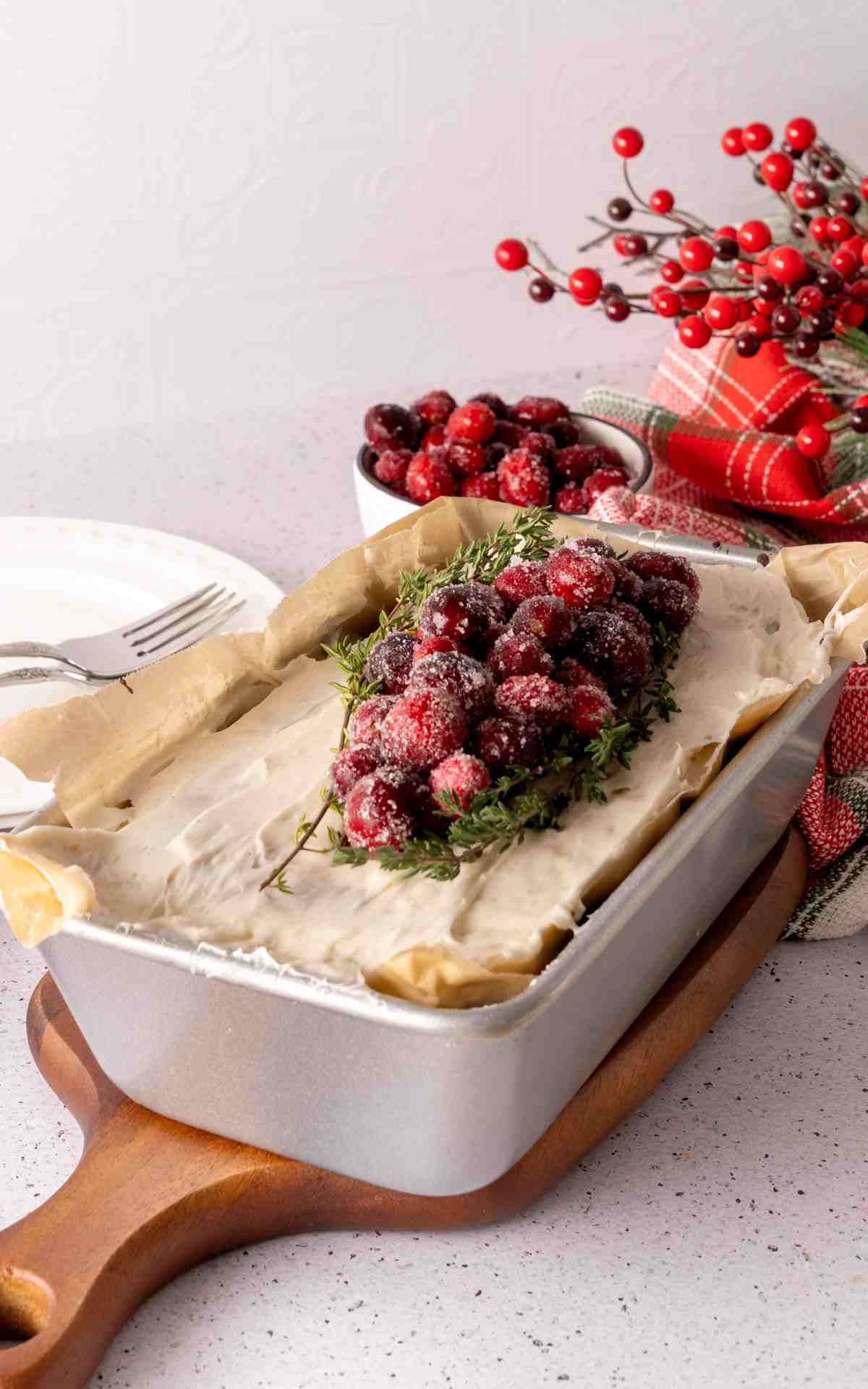 A freshly baked and frosted gingerbread cake with a loaf pan on a wooden board.