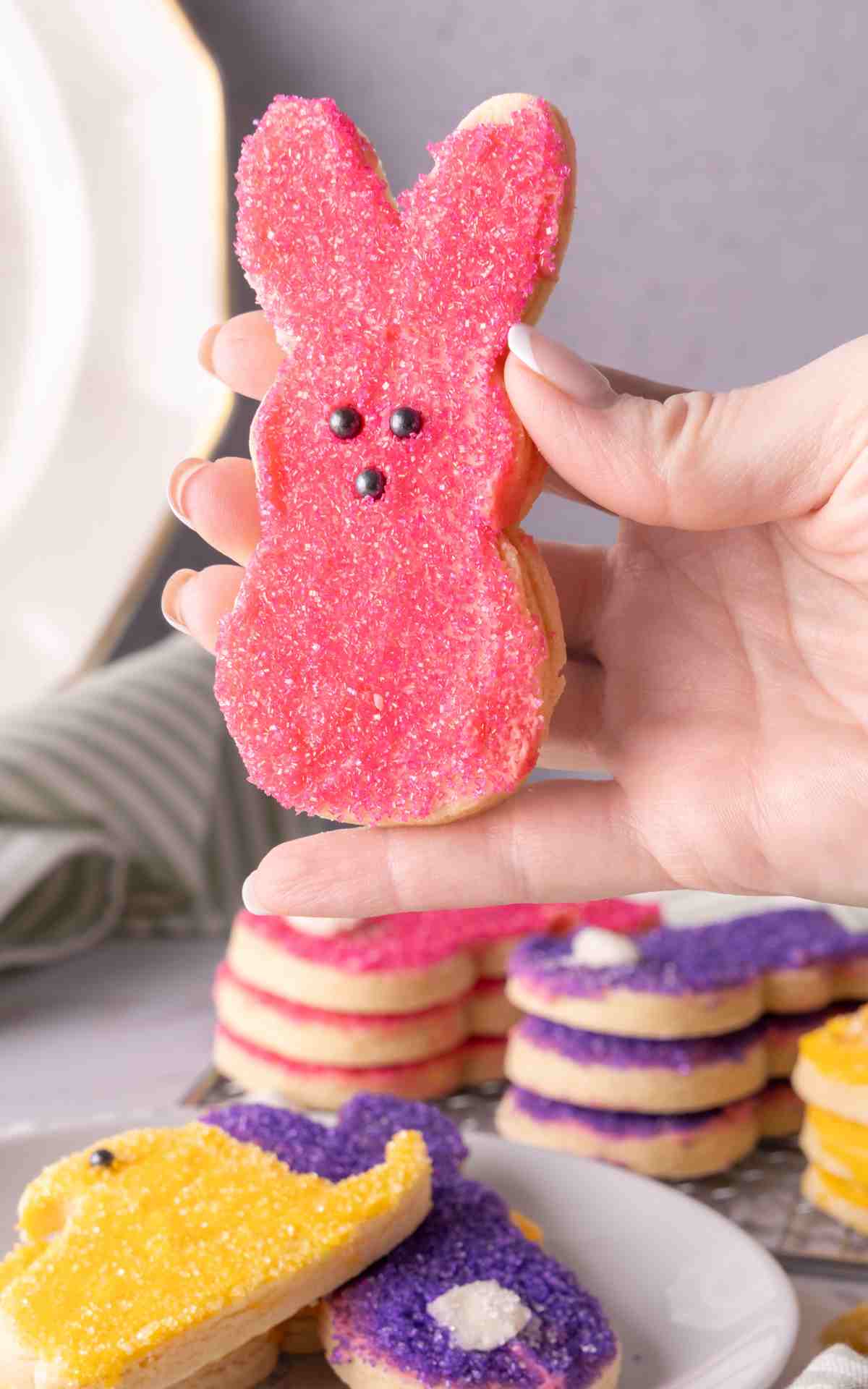A hand holding up a bunny shaped soft frosted cut out sugar cookie.
