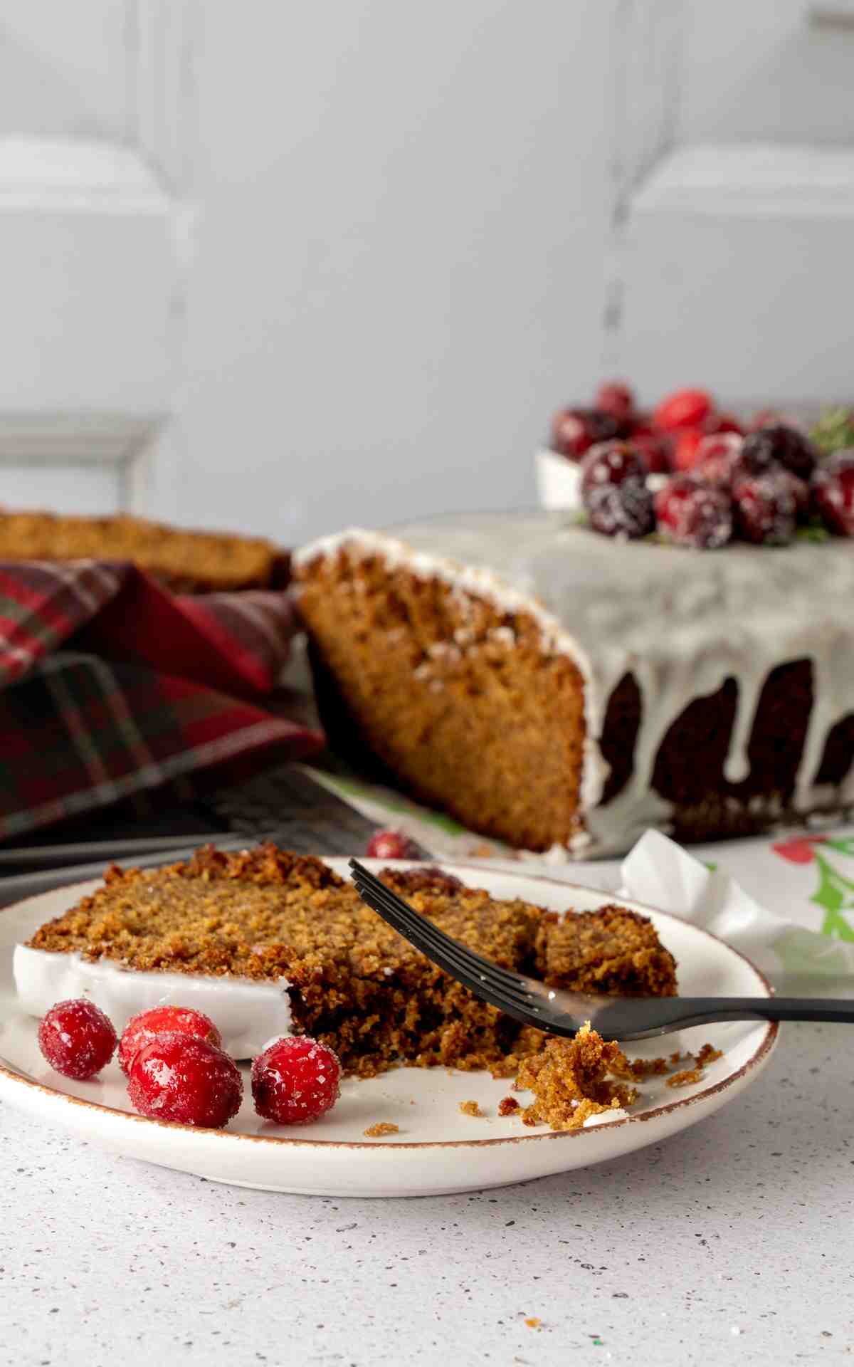 A slice of old fashioned gingerbread cake with a fork cut into it on a plate.