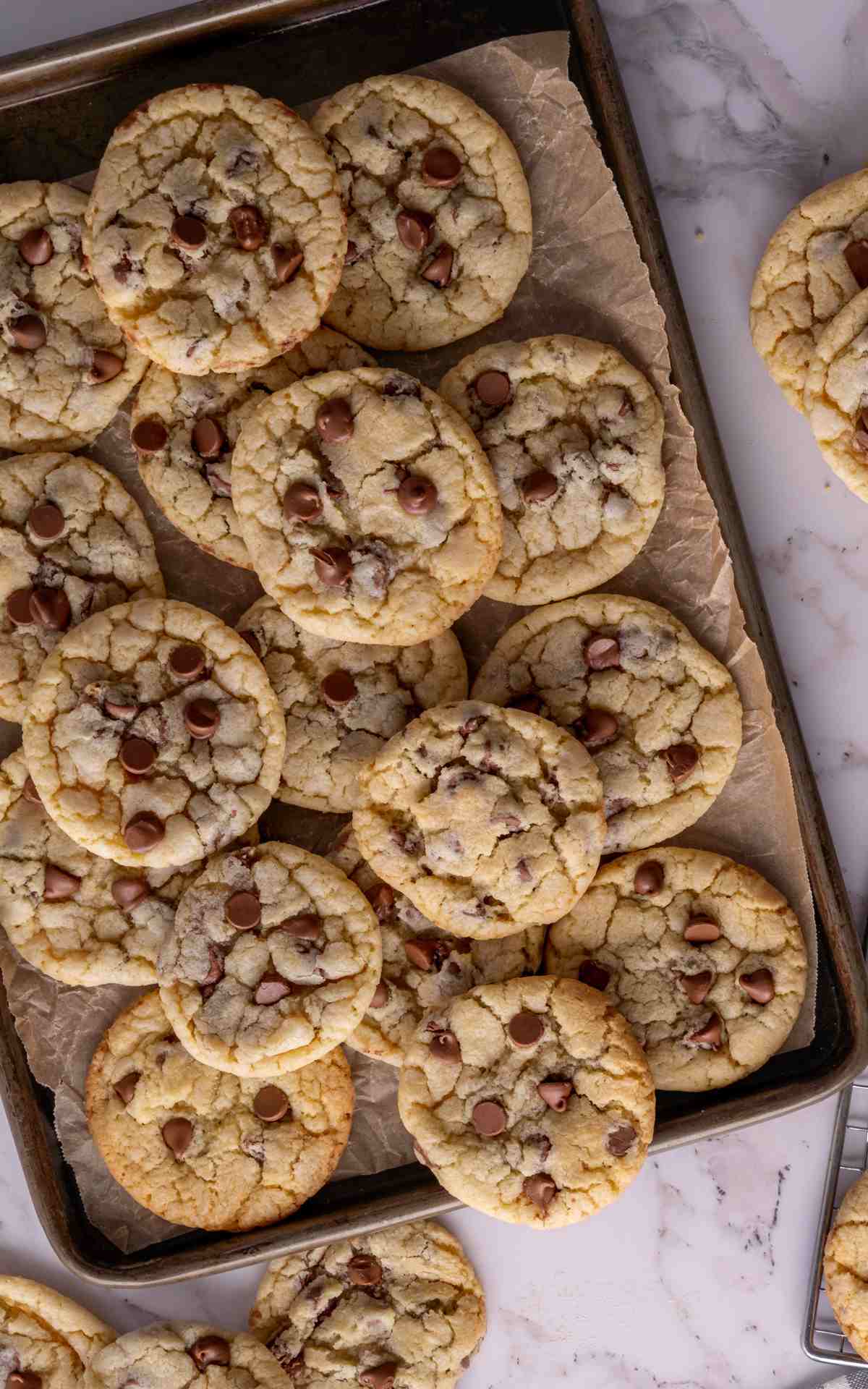 Chocolate chip sour cream cookies scattered on a baking sheet.