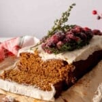 Sliced cake mix gingerbread loaf frosted with cream cheese frosting and cranberries.