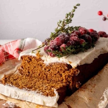 Sliced cake mix gingerbread loaf frosted with cream cheese frosting and cranberries.