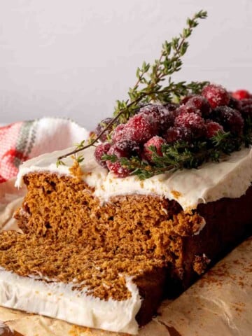 Sliced cake mix gingerbread loaf frosted with cream cheese frosting and cranberries.