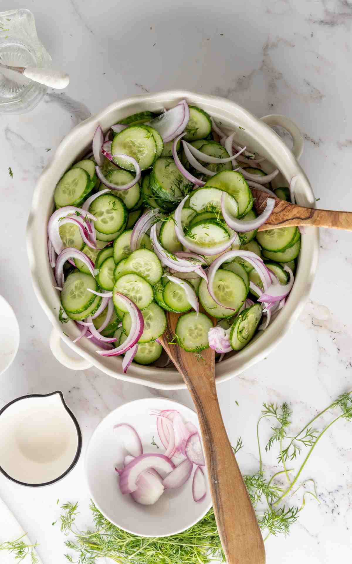 Cucumber vinegar salad in a ceramic bowl with serving utensils.