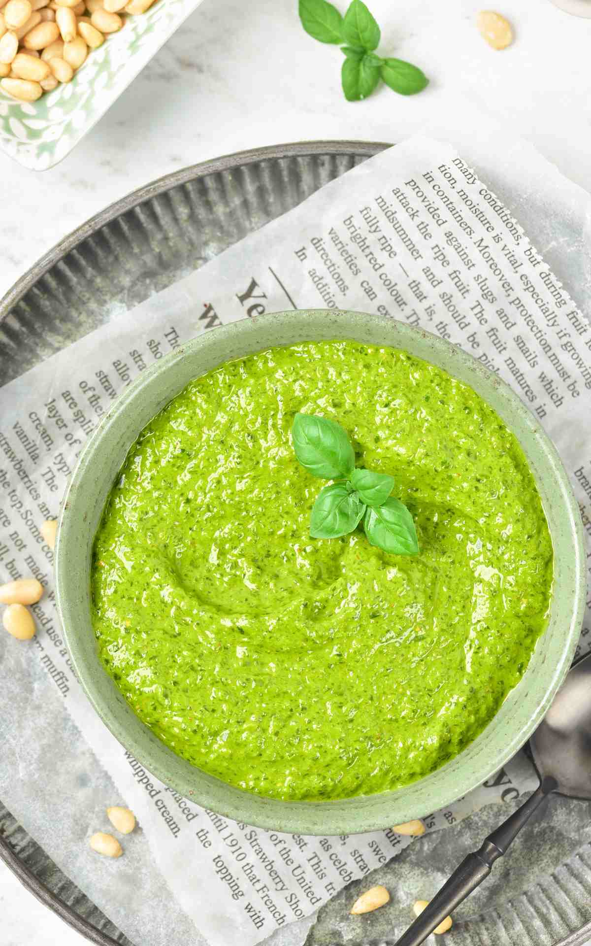 Homemade basil pesto in a bowl with basil leaves.