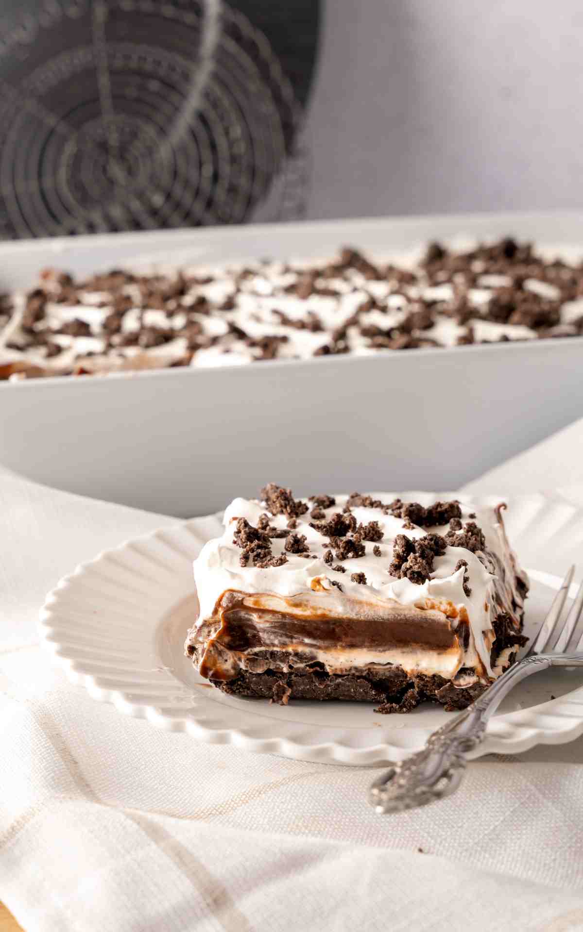 A slice of easy chocolate lasagna with crumbled cookies on top of the Cool Whip.