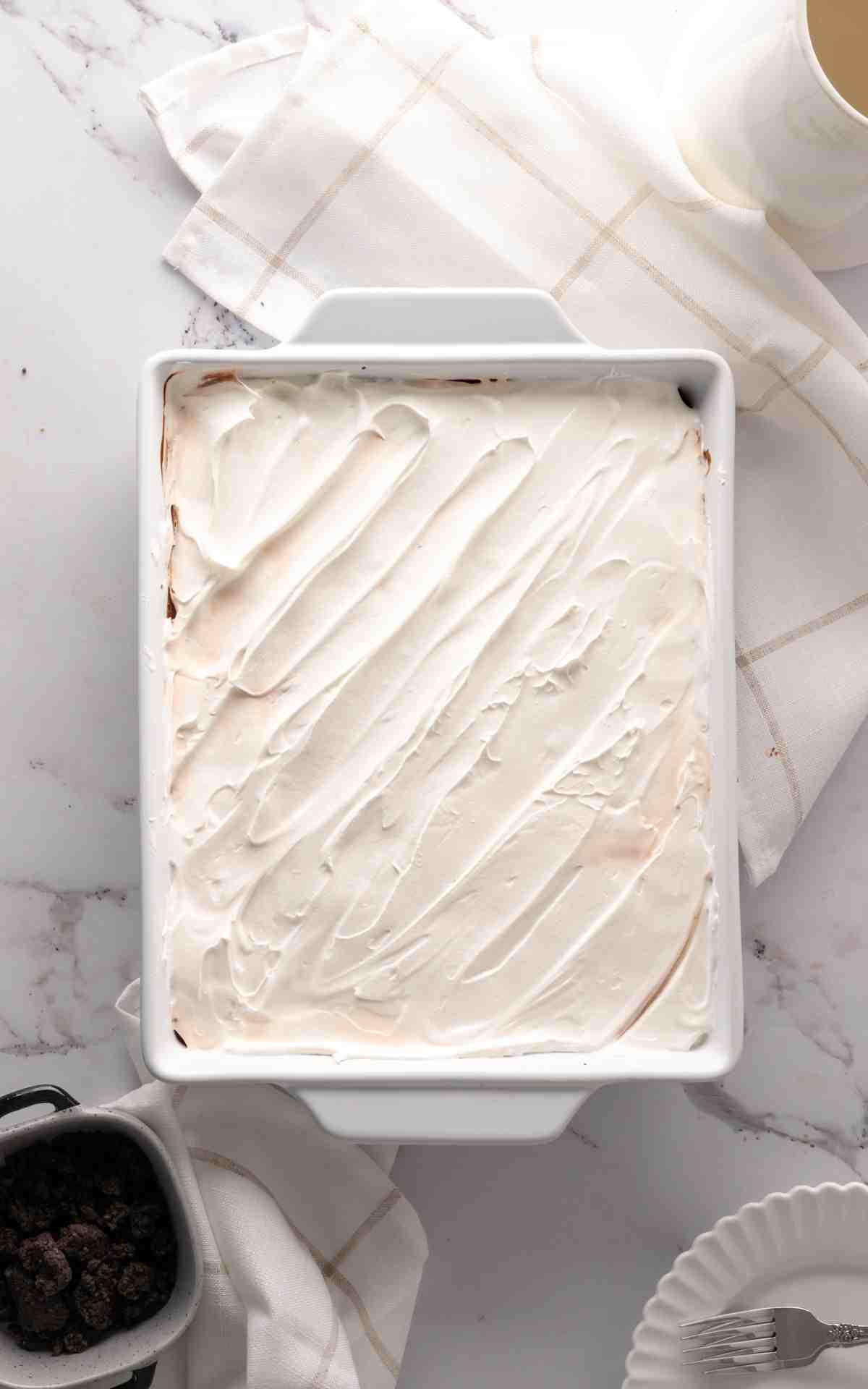 Chocolate layered dessert with cool whip spread on top.