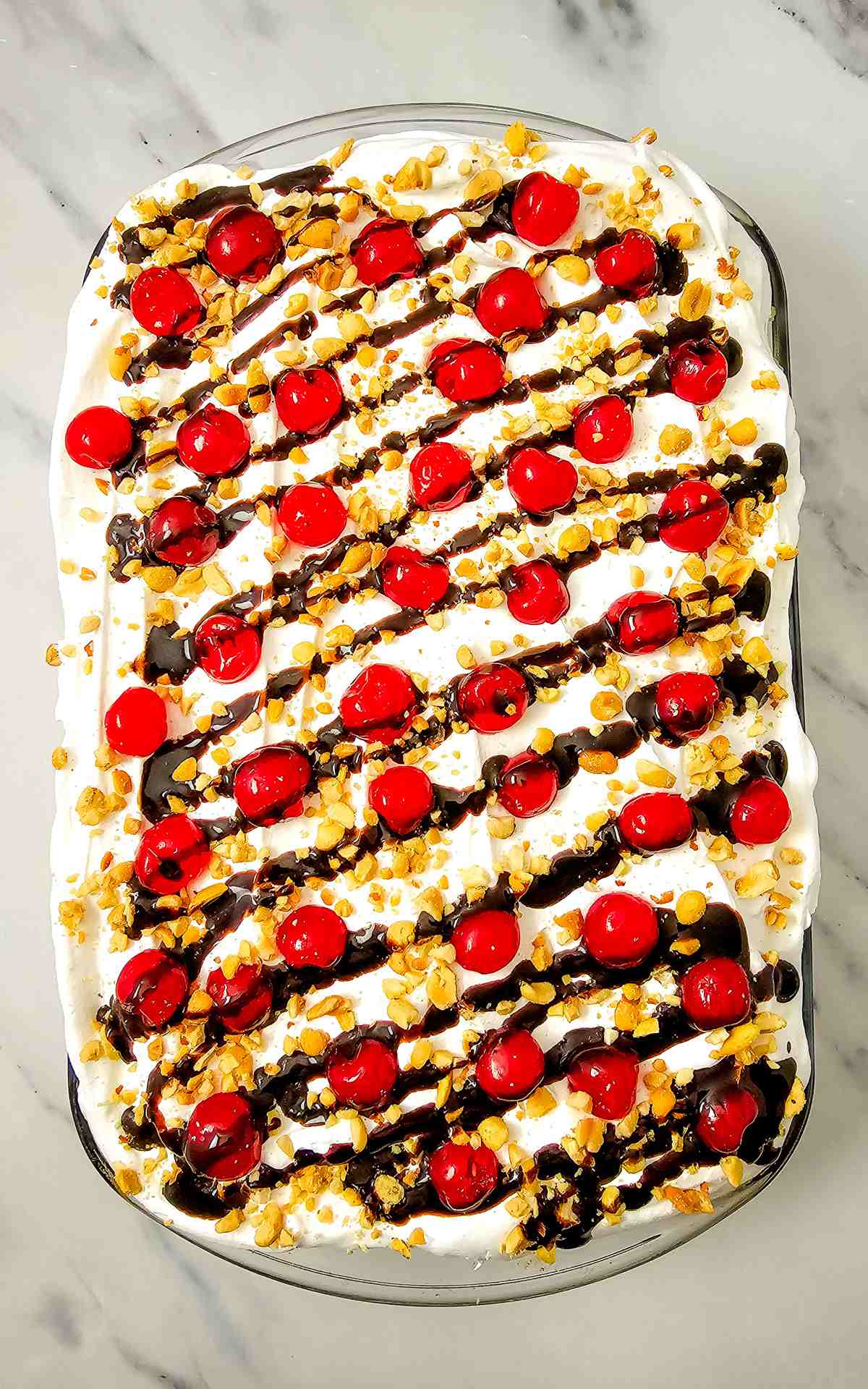 Easy banana split cake made with cake mix topped with cherries nuts and cool whip.